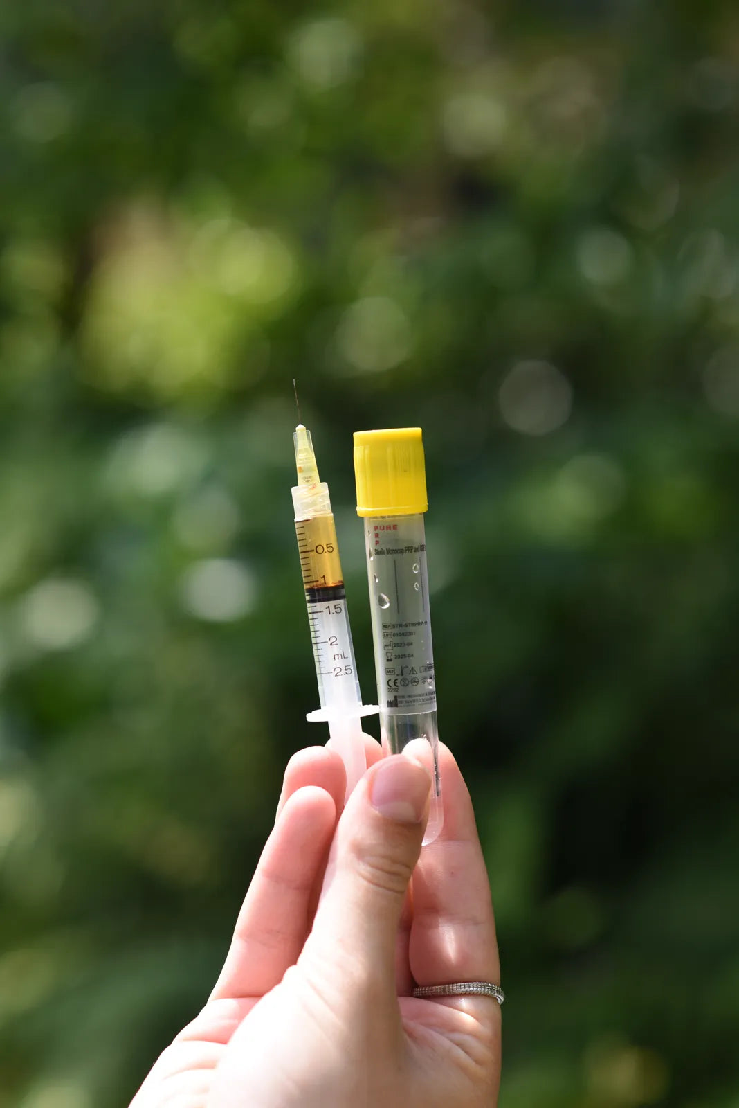 Golden plasma drawn into a syringe next to a PRP Pure tube